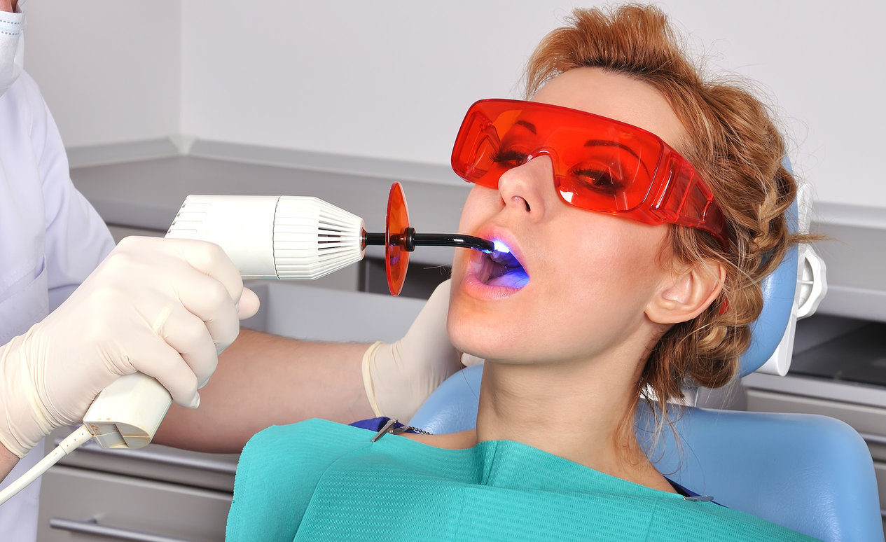 Vöröshajú nő ül egy fogászati székben fogtömés közben.