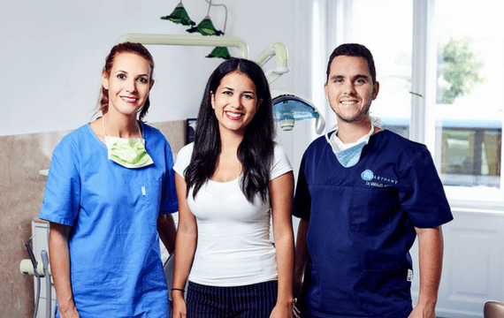 Dr. Varajti Artúr fogorvos, fogászati asszisztens és páciens állnak egymás mellett és mosolyognak a bölcsességfog eltávolítás után.