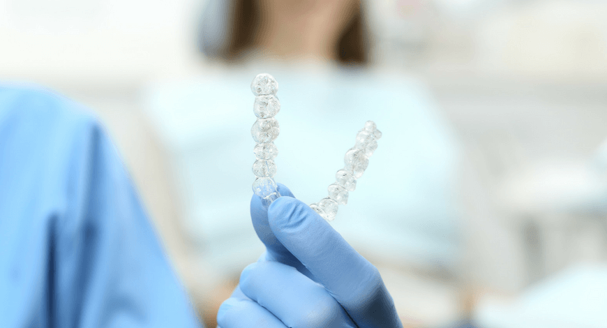 Dr. Friedreich Dóra, az Artdent fogszabályozó szakorvosa egy láthatatlan fogszabályozó készüléket tart a kezében a budapesti fogászati rendelőben.