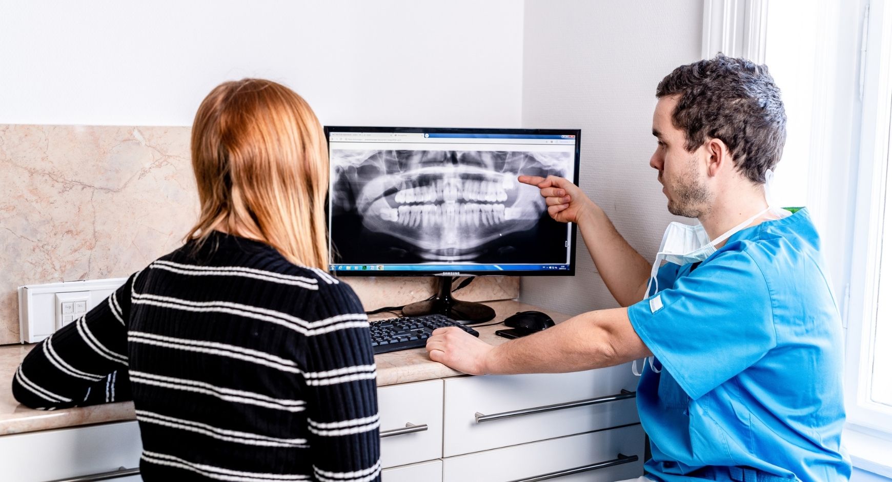 Bölcsességfog műtét előtti konzultáció közben Dr. Varajti Artúr és páciense a budapesti fogászati rendelőben.