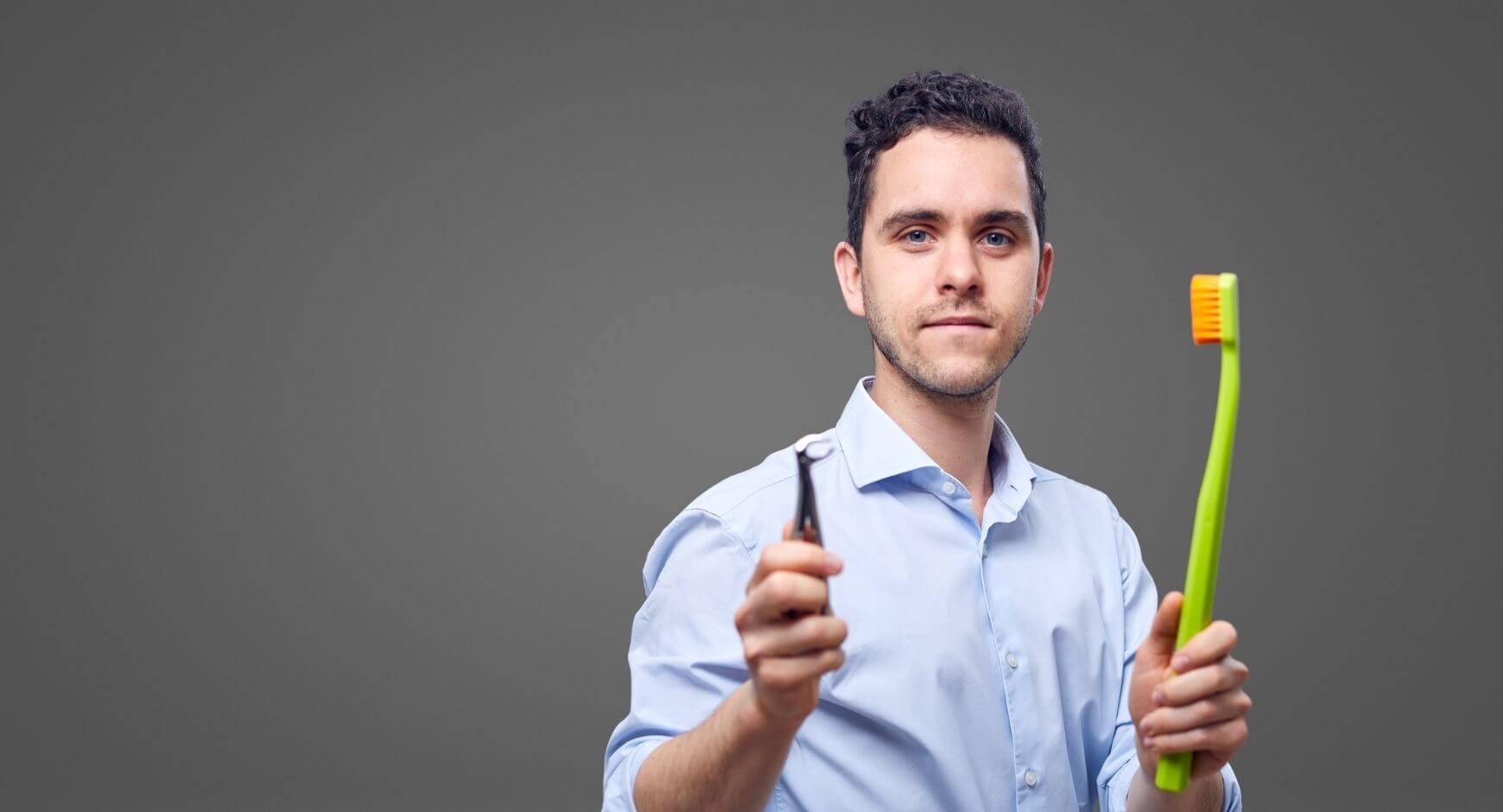 Dr. Varajti Artúr fogorvos és szájsebész kezében egy fogkefe és egy fogó.